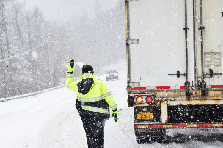 Brattleboro, Vt., Police Officer Ryan Washburn helps direct traffic on Route 9 after a tractor-trailer got stuck in the snow during a snowstorm on Monday, Jan. 17, 2022. (Kristopher Radder/The Brattleboro Reformer via AP)