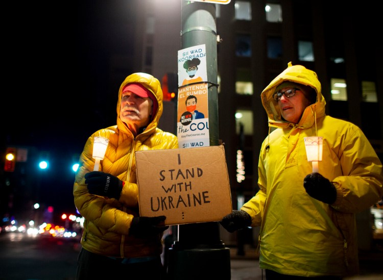 Chuck Morrison and Gail Turner of Portland hold a sign to show their support for Ukraine at Monument Square in Portland on Thursday, evening.