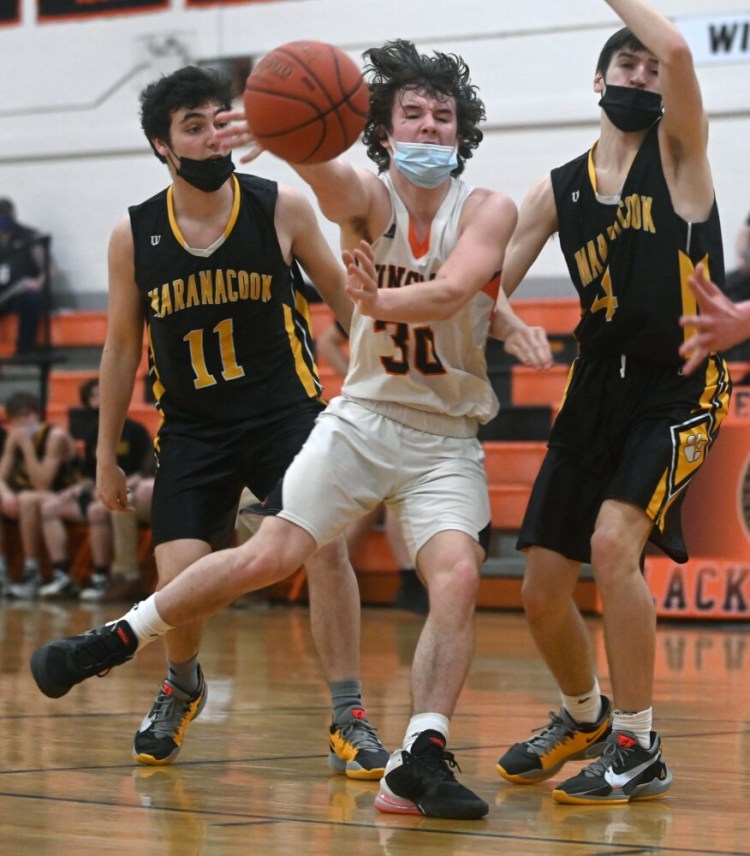  Winslow's Andrew Poulin dishes the ball as Maranacook defenders Nick Florek, left, and Brayden St. Pierre apply pressure during a Kennebec Valley Athletic Conference Class B game Thursday night in Winslow.