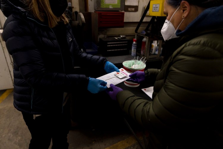 Amanda Lachance hands off a rapid COVID-19 test to Laura Coroi to let it process at Yarmouth Public Works on Monday, February 7, 2022. 