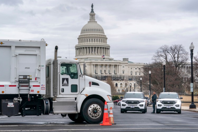 Heavy vehicles, including garbage trucks and snow plows, are set near the entrance to Capitol Hill at Pennsylvania Avenue and 3rd Street NW on Tuesday. Some D.C. convoy organizers have spoken of plans to briefly roll through the city, then focus on shutting down the Beltway, which encircles the Washington metropolitan area.