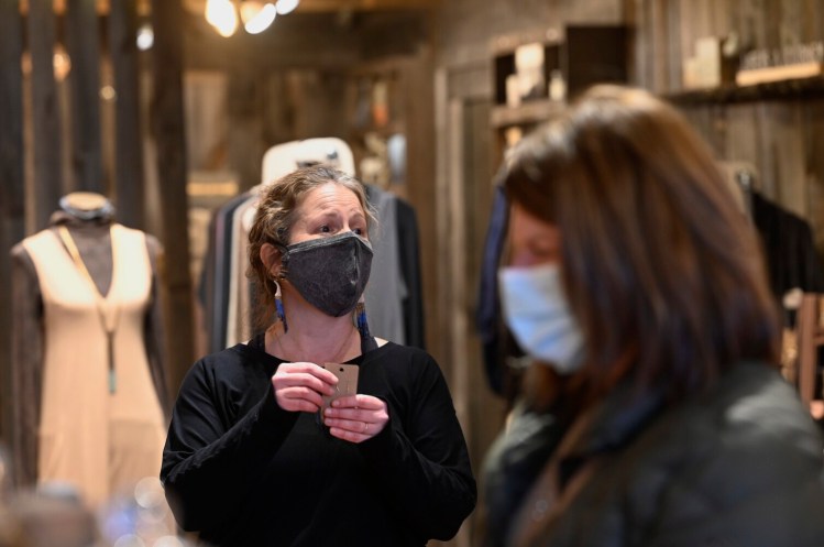 Leslie Smith, director of operations for Suger, talks with customers shopping at the store on Commercial Street in Portland on Friday. While masks are optional for workers at Suger, Smith chooses to wear them when customers wearing masks enter the store.