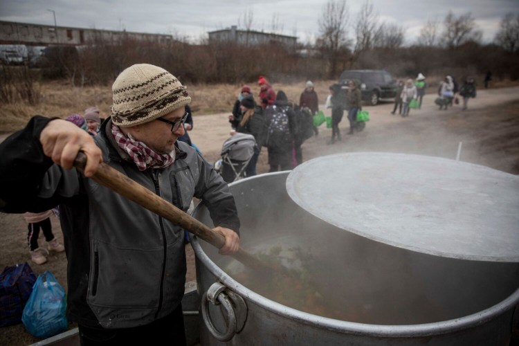 Czech volunteer Lukas Saranga cooks a soup in a giant pot for refugees fleeing Ukraine at the train station at border crossing of Medyka, Poland, Tuesday, March 8, 2022. U.N. officials said Tuesday that the Russian onslaught has forced 2 million people to flee Ukraine. It has trapped others inside besieged cities that are running low on food, water and medicine amid the biggest ground war in Europe since World War II. (AP Photo/Visar Kryeziu)