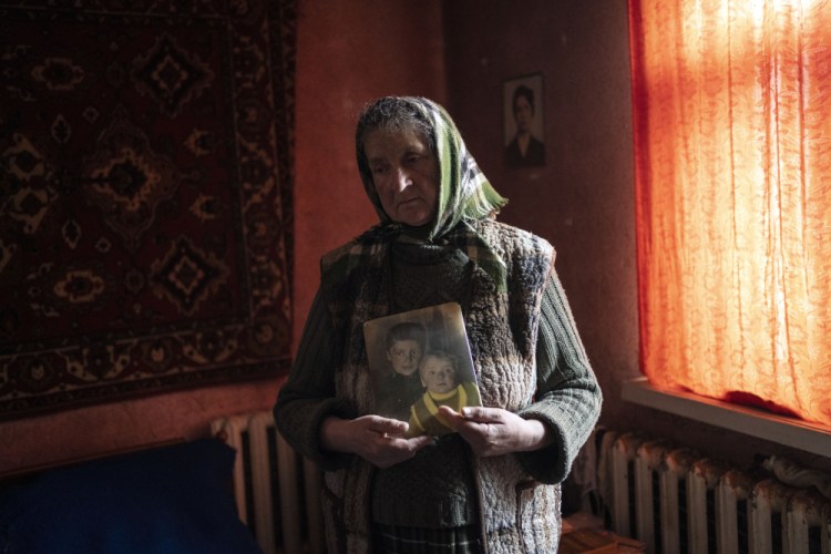 Nadiya Trubchaninova, 70, stands in her bedroom holding a portrait of her sons Oleg Trubchaninov, 46, and Vadym, 48, who was killed by Russian soldiers last March 30 in Bucha, in the outskirts of Kyiv, Ukraine.