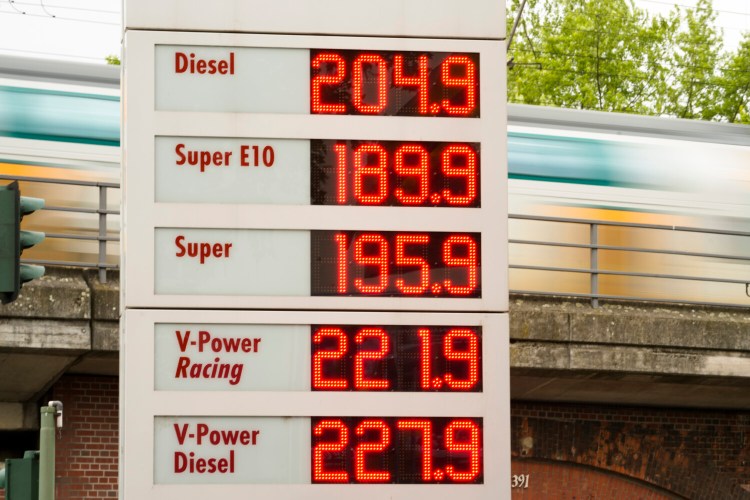 A public transport train drive behind a display with fuel prices at a gas station et in Berlin, Germany, Sunday, June 19, 2022. People across the world are confronted with higher fuel prices as the war in Ukraine and lagging output from producing nations drive prices higher. Drivers are looking at the numbers on the gas pump and rethinking their habits and finances, pushing some to walk, bike or use public transport. (AP Photo/Markus Schreiber)