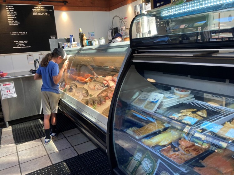 A boy studies the fish counter inside Browne Trading Co. The famous fishmonger and gourmet market has started serving lunch. 