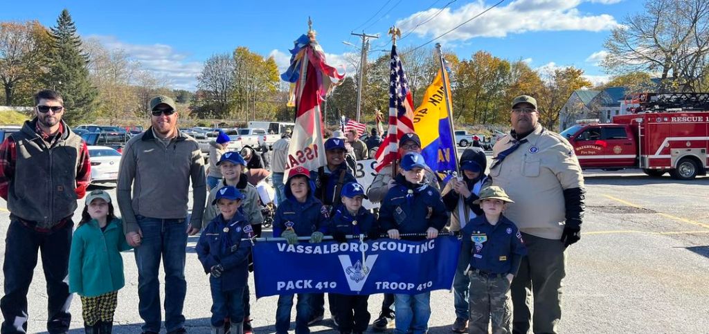 Vassalboro Scouts at the Waterville Veterans Day Parade: Row 1 (L to R) - Tiger Scout Kasen Maroon, Wolf Scout Beckett Metcalf, Tiger Scout Greyson Malloy, Wolf Scout John Gray, and Wolf Scout Lux Reynolds. Row 2 (L to R) - Tiger Den Leader Shane Maroon, Dragon Scout Lila Reynolds, Asst. Cubmaster/Wolf Den Leader Chris Reynolds, Webelos Scout Anthony Malloy, Arrow of Light Scout Christopher Santiago, Arrow of Light Scout William Vincent, Webelos Scout Henry Gray, Asst. Scoutmaster/Cubmaster Christopher Santiago