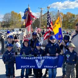 Vassalboro Scouts at the Waterville Veterans Day Parade: Row 1 (L to R) - Tiger Scout Kasen Maroon, Wolf Scout Beckett Metcalf, Tiger Scout Greyson Malloy, Wolf Scout John Gray, and Wolf Scout Lux Reynolds. Row 2 (L to R) - Tiger Den Leader Shane Maroon, Dragon Scout Lila Reynolds, Asst. Cubmaster/Wolf Den Leader Chris Reynolds, Webelos Scout Anthony Malloy, Arrow of Light Scout Christopher Santiago, Arrow of Light Scout William Vincent, Webelos Scout Henry Gray, Asst. Scoutmaster/Cubmaster Christopher Santiago