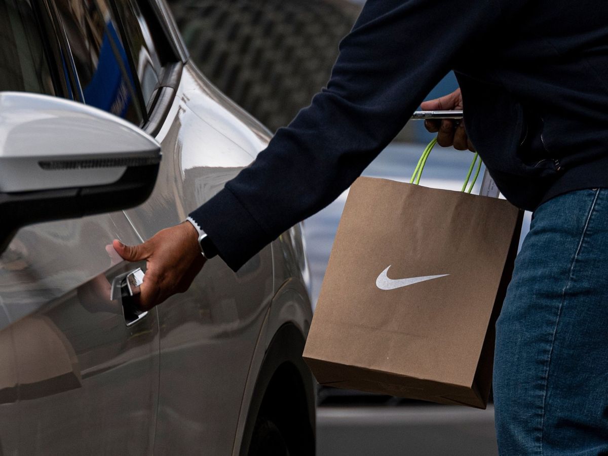 A person wearing a protective mask carries a Nike branded shopping bag in front of a Nike store in San Francisco, California, U.S., on Monday, March 15, 2021.