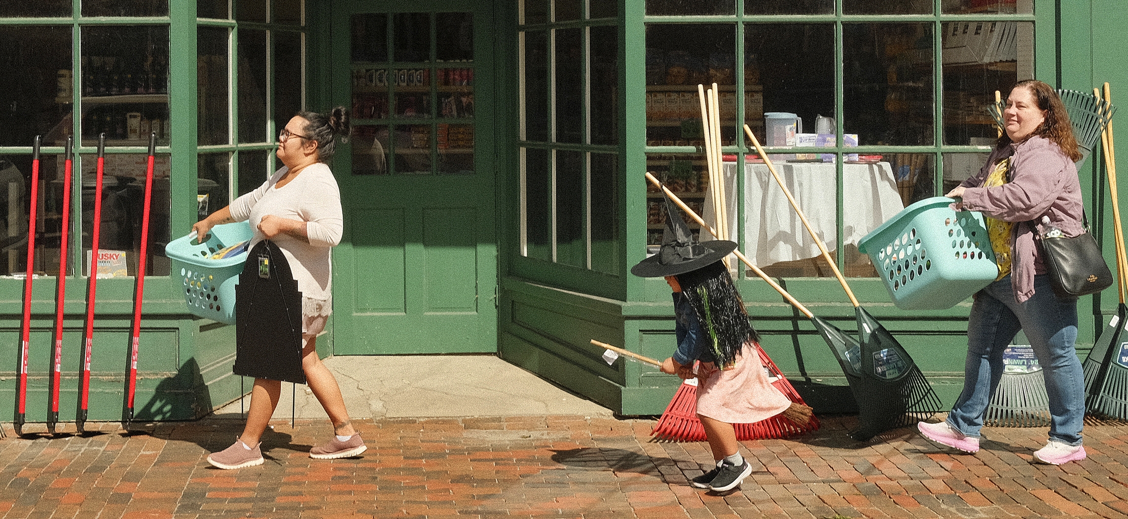 A witch on a broomstick emerges Sunday on the sidewalk in front of Renys in downtown Gardiner. Eliana Geronimo, 5, was test flying the costume she selected with her mother, Michelle, right, while shopping with their friend, Alize Blas, left. The Lewiston residents said garden clean-up tools and Halloween decorations at Renys are some of the best harbingers of autumn in Maine.