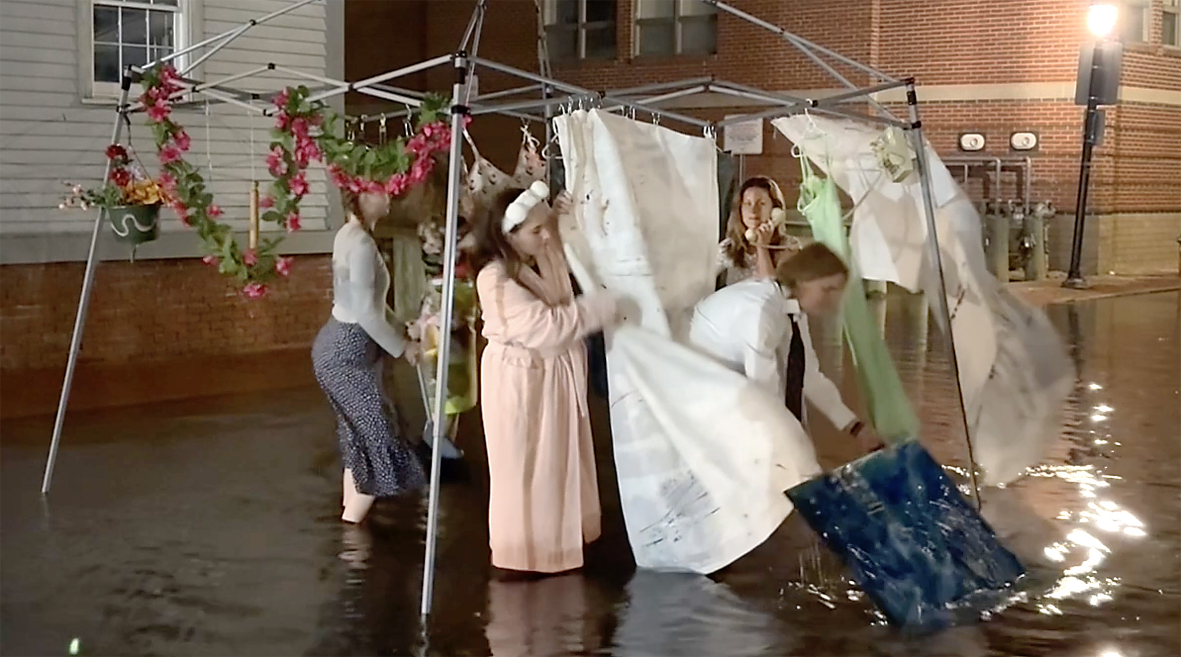 Actors portray a family trying to cook, clean and stay safe while floodwaters rise in this performance art piece from painter Judith Greene Janse titled “Everything Has Changed.” The performance was part of the Gulf of Maine Research Institute’s midnight flooding walk Wednesday at Portland Pier, when the spring’s high-water season peaked with an 11-foot-8-inch tide. Screen capture from video by Penelope Overton/Portland Press Herald